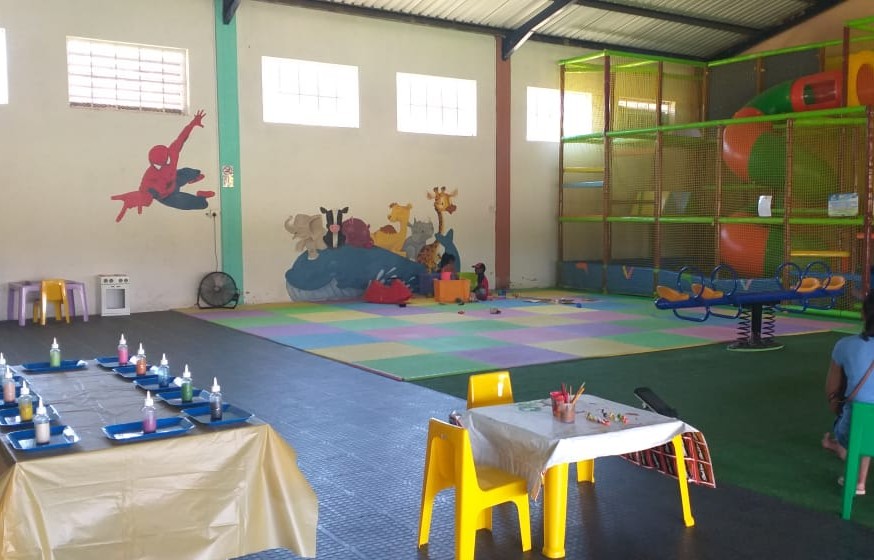 Long party table with colourful chairs facing the jumping castle and soft-play area