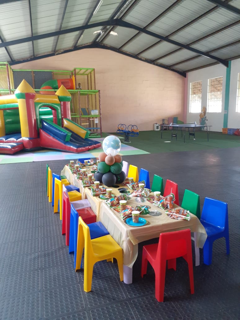 Long party table set for a boy's birthday with jumping castle in the background